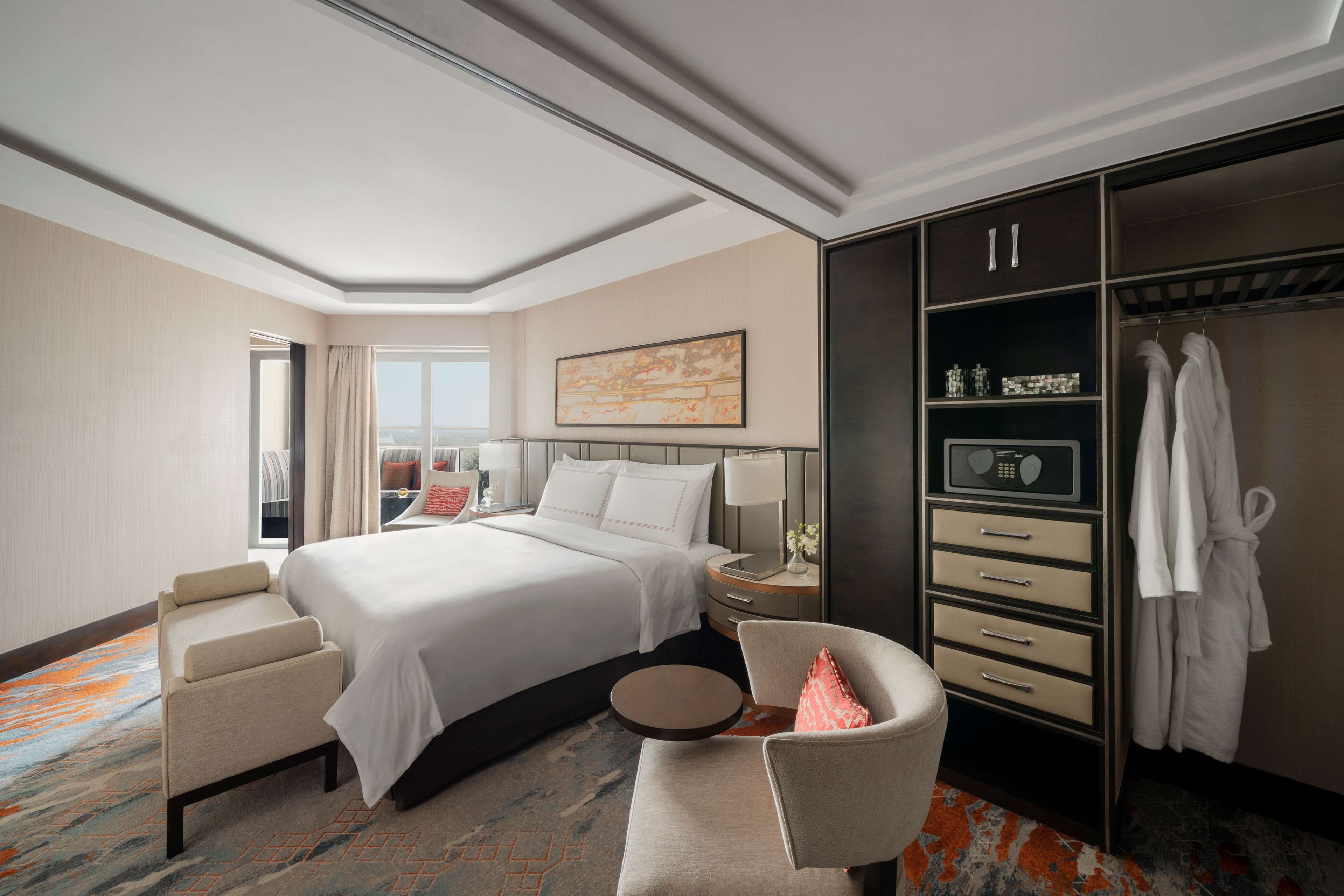 Een hotelkamer met een groot bed, een zithoek, een kledingkast en een raam met gordijnen.