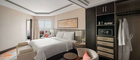 A hotel room with a large bed, a seating area, a wardrobe, and a window with curtains.