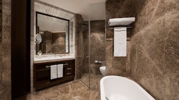 A modern bathroom with a marble floor, a freestanding bathtub, a large mirror, and a glass-enclosed shower.