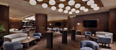 A modern lobby with sofas, tables, and a TV.