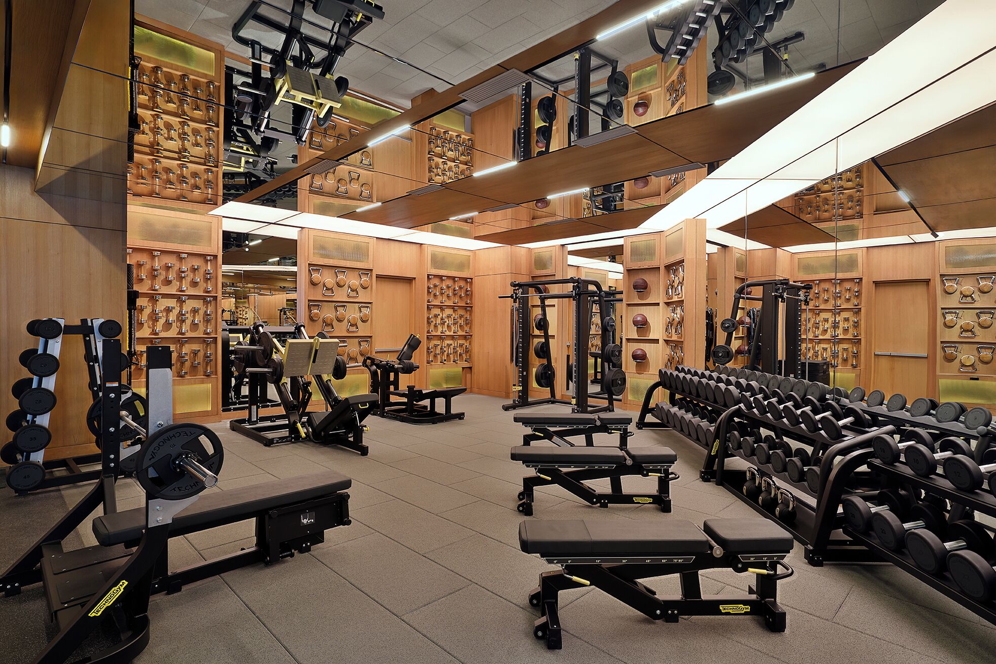 Une salle de sport équipée de divers appareils d’exercice, notamment des bancs, des haltères et des machines de musculation.