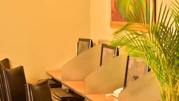 A conference room with a long table, black leather chairs, a potted plant, and a colorful abstract painting on the wall.