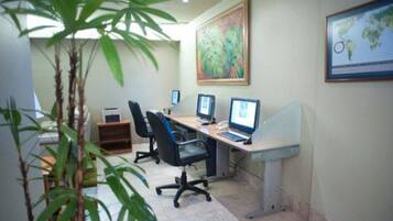 A conference room with three desktop computers, two office chairs, and a large painting on the wall.