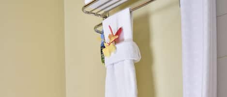 A bathroom with a toilet, a towel rack with towels, and a toilet paper holder.