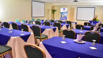 A conference room with multiple tables set for a meeting, equipped with nameplates, water glasses, and notepads.