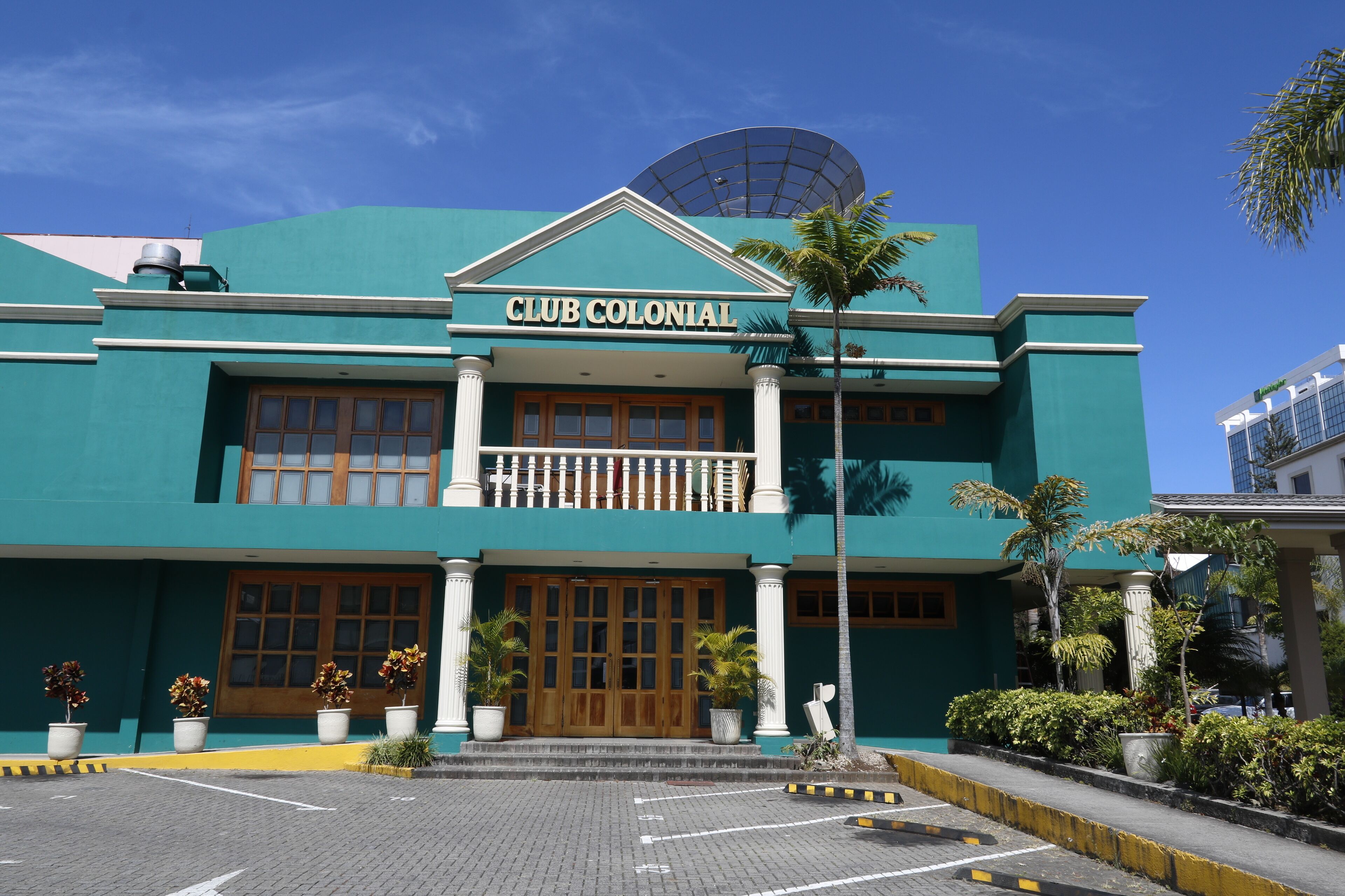 A building with a sign reading "CLUB COLONIAL" and a balcony with white balustrades.