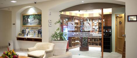 A hotel lobby with a reception desk, seating area, and a wine rack.