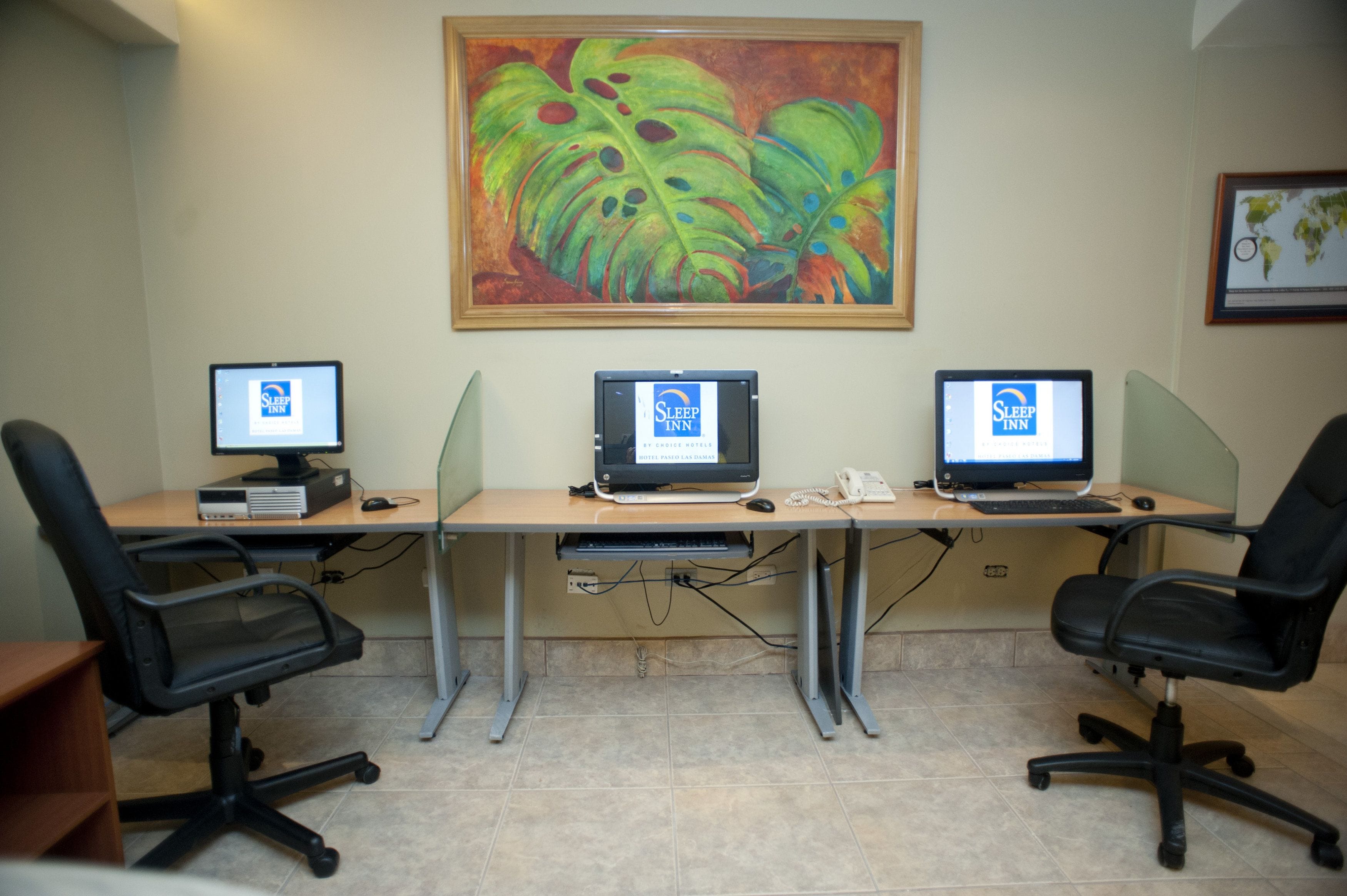 Une salle de conférence équipée de trois bureaux, chacun doté d’un ordinateur et d’un téléphone.