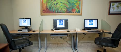 A conference room with three desks, each with a computer and a telephone.