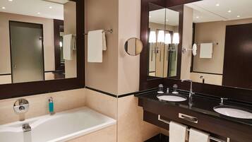 A modern bathroom with two sinks, a bathtub, and a large mirror.