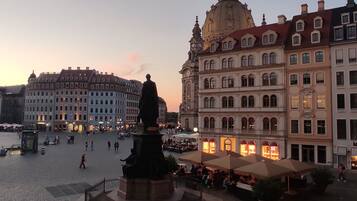Ein öffentlicher Platz mit einer Statue, historischen Gebäuden und Sitzgelegenheiten im Freien.