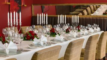 A long dining table set with white tablecloths, candles, and red flowers.