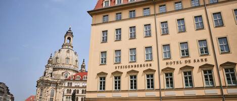 A historic building with the sign "STEIGENBERGER HOTEL DE SAXE" and a prominent tower with a dome.