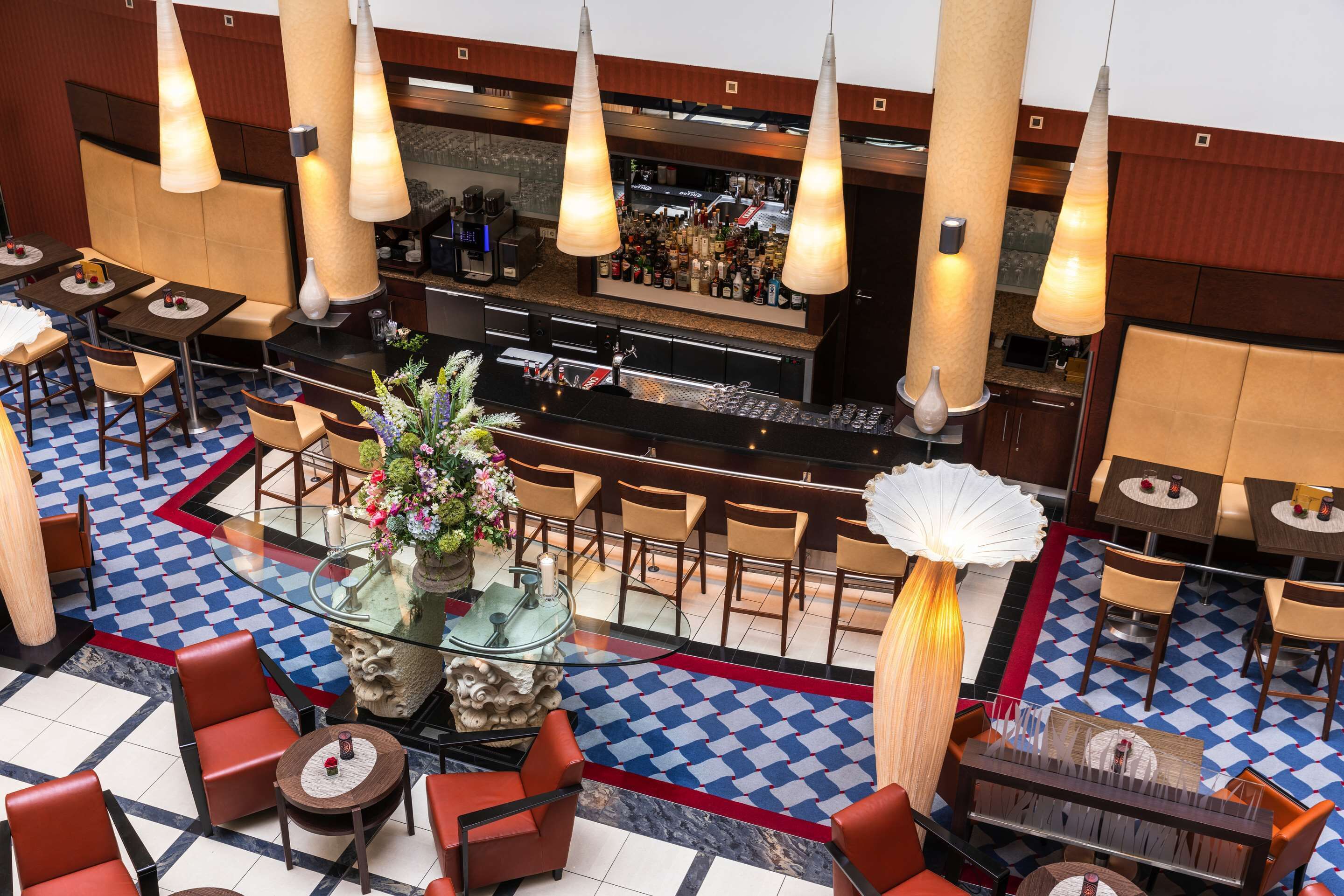 Een hotel lobby met een bar, zithoeken en een decoratief middelpunt.