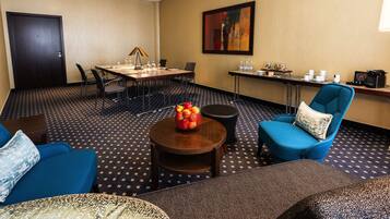 A conference room with a table, chairs, a coffee station, and a blue armchair.