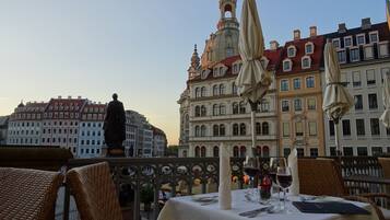 A table set for dining with a view of historic buildings and a statue in the background.