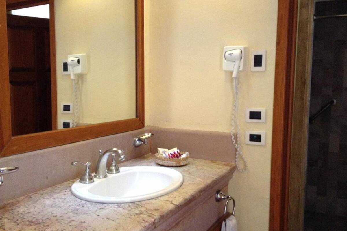 A bathroom with a sink, mirror, towel rack, and a shower area.