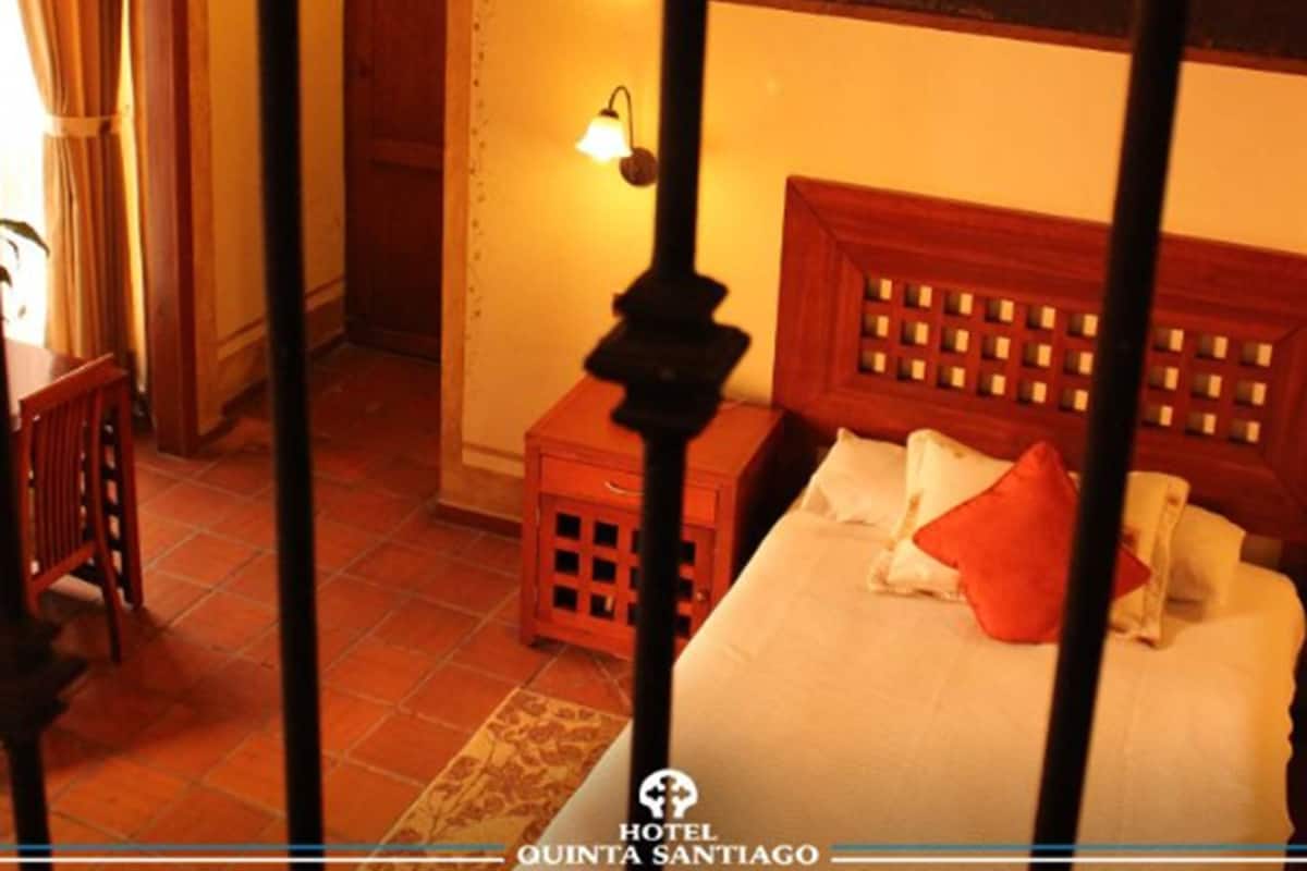 A hotel room with a bed, a nightstand, a lamp, and a view of the balcony.