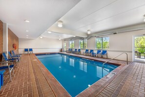 En swimmingpool med blått vatten, omgiven av blå stolar och ett tegelgolv.