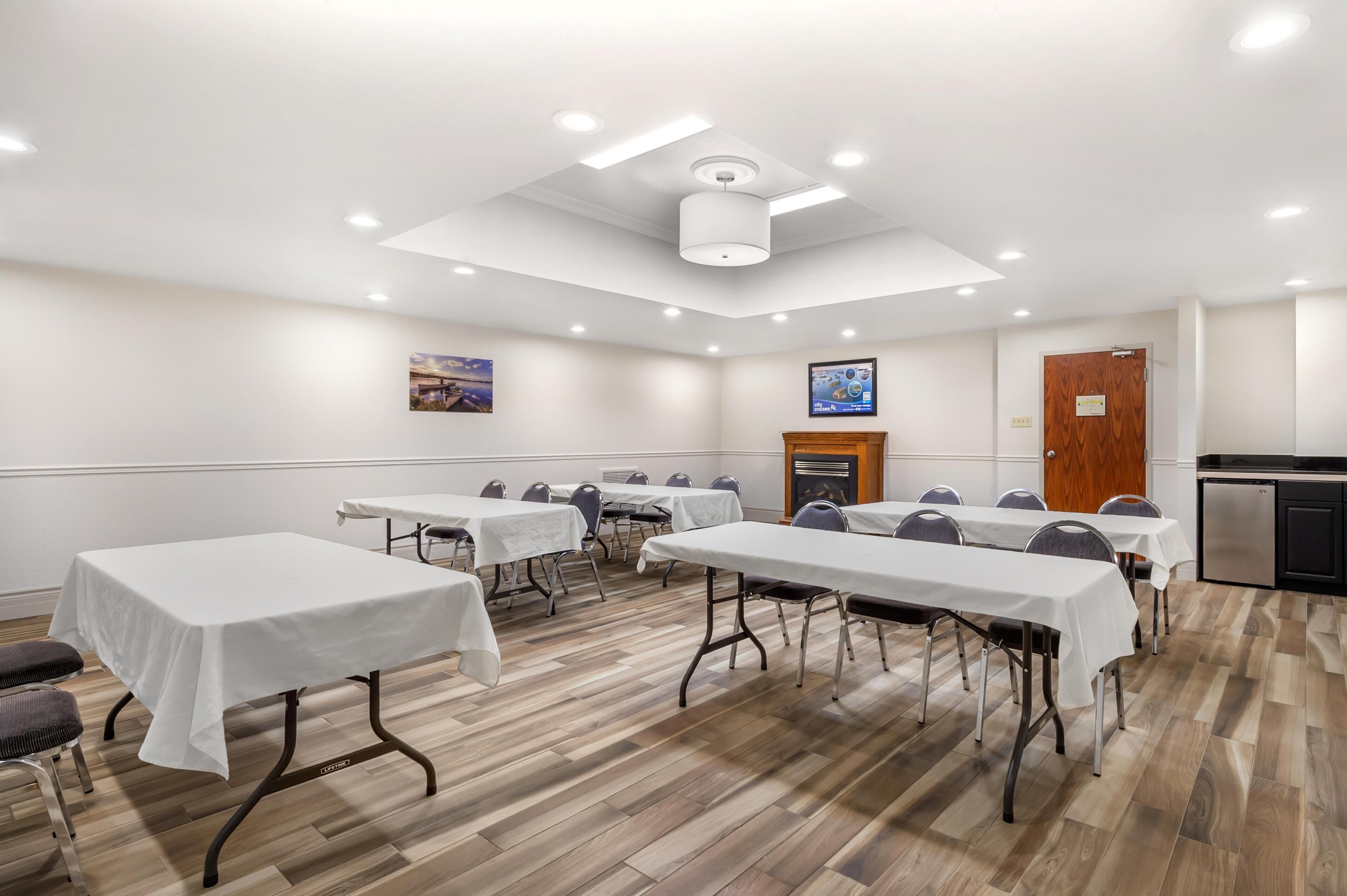 A conference room with tables, chairs, a fireplace, and a kitchenette.