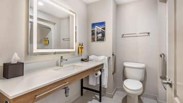 Un baño moderno con un espejo grande, lavamanos dobles, inodoro y zona de ducha.