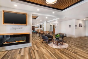 A modern interior with a fireplace, wooden flooring, and a dining area with chairs and tables.