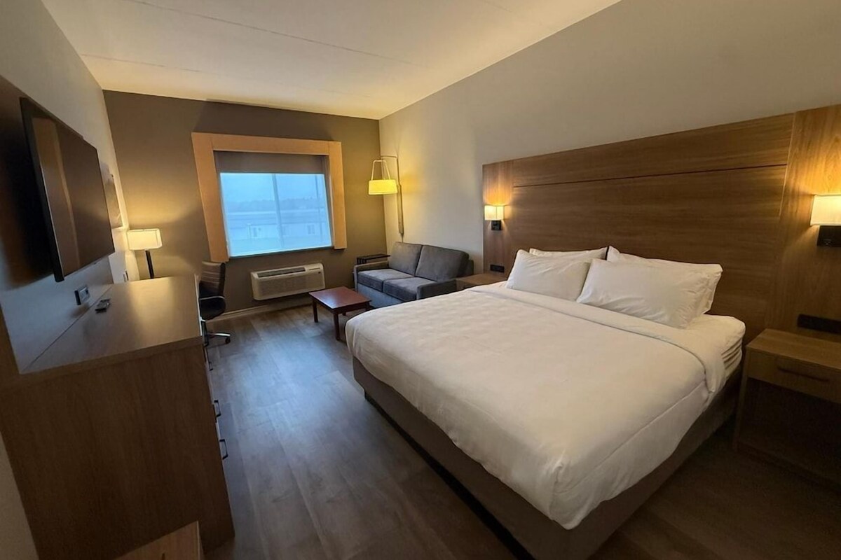 Une chambre d’hôtel avec un grand lit, un bureau, une chaise, une télévision et une fenêtre.
