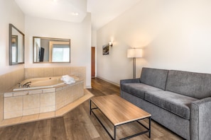 Ein modernes Badezimmer mit einer Badewanne, einem grauen Sofa und einem Holztisch.
