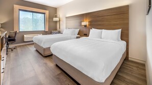 Une chambre d’hôtel avec deux lits, un bureau, une chaise et une grande fenêtre.