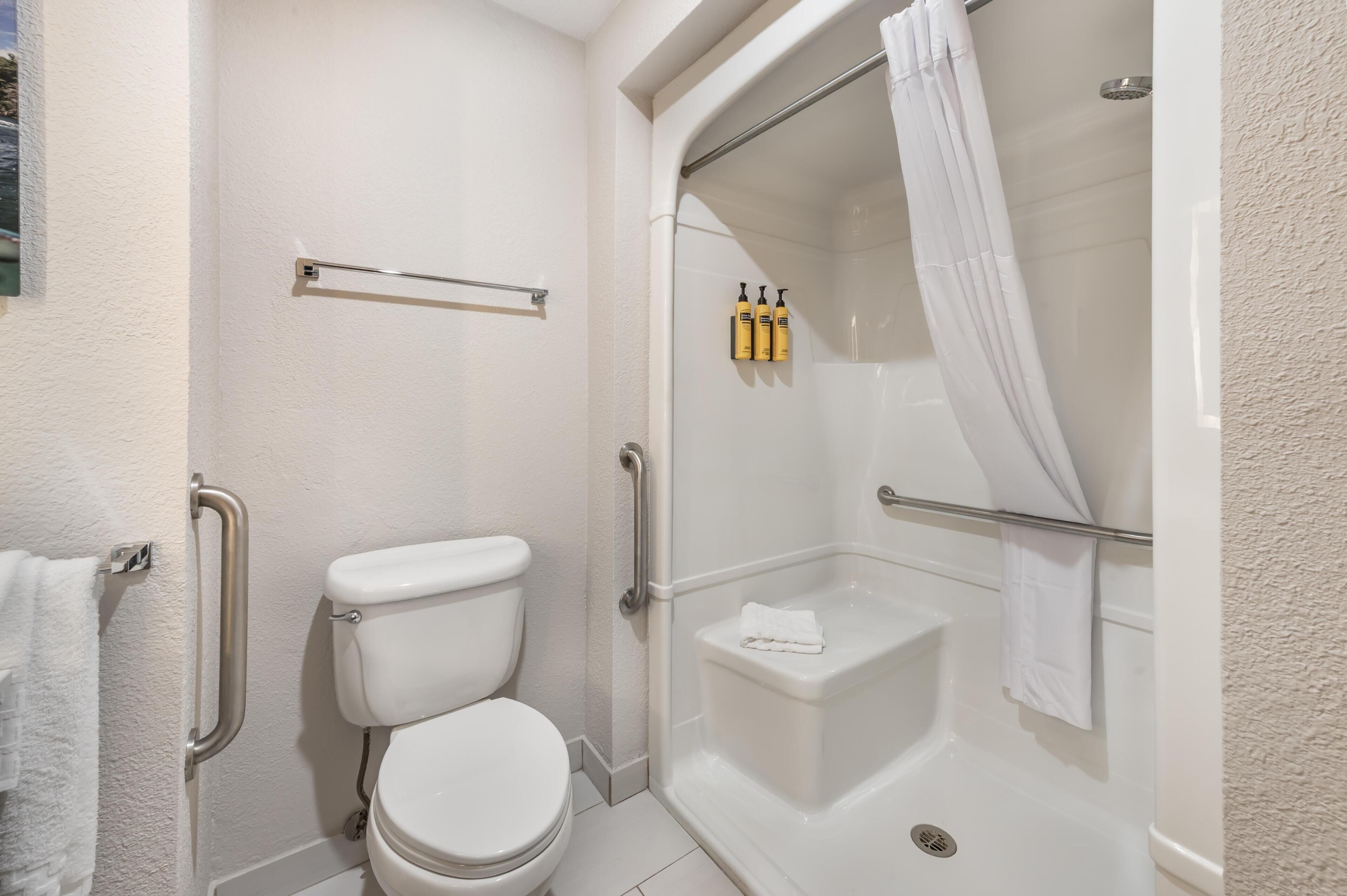 Un baño con inodoro, ducha con puerta de cristal y toallero.