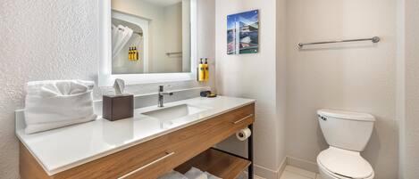 Een badkamer met een witte wastafel, een houten wastafelmeubel en een wit toilet.