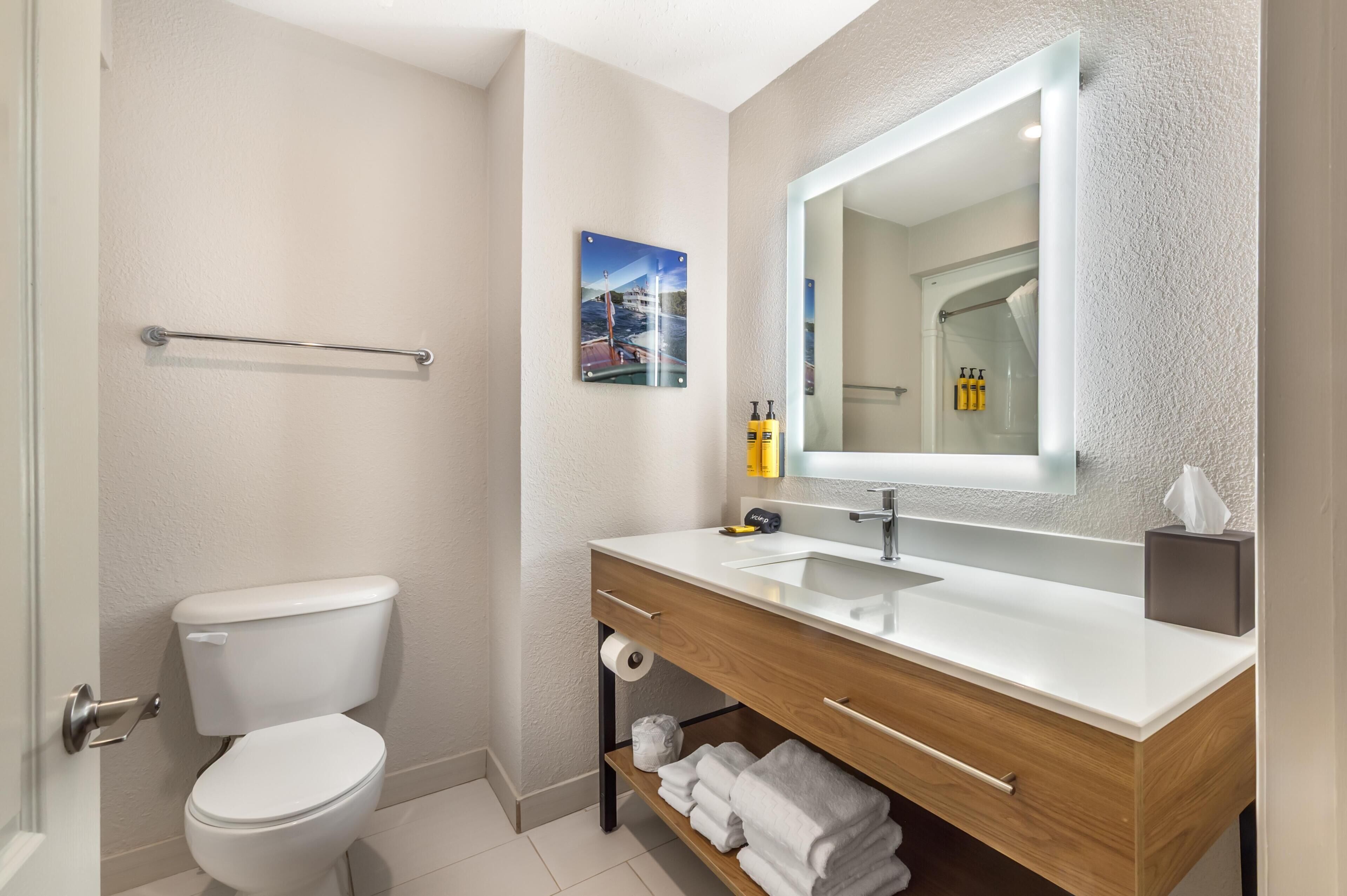 Ein modernes Badezimmer mit Toilette, Waschbecken, Spiegel und Handtuchhalter.