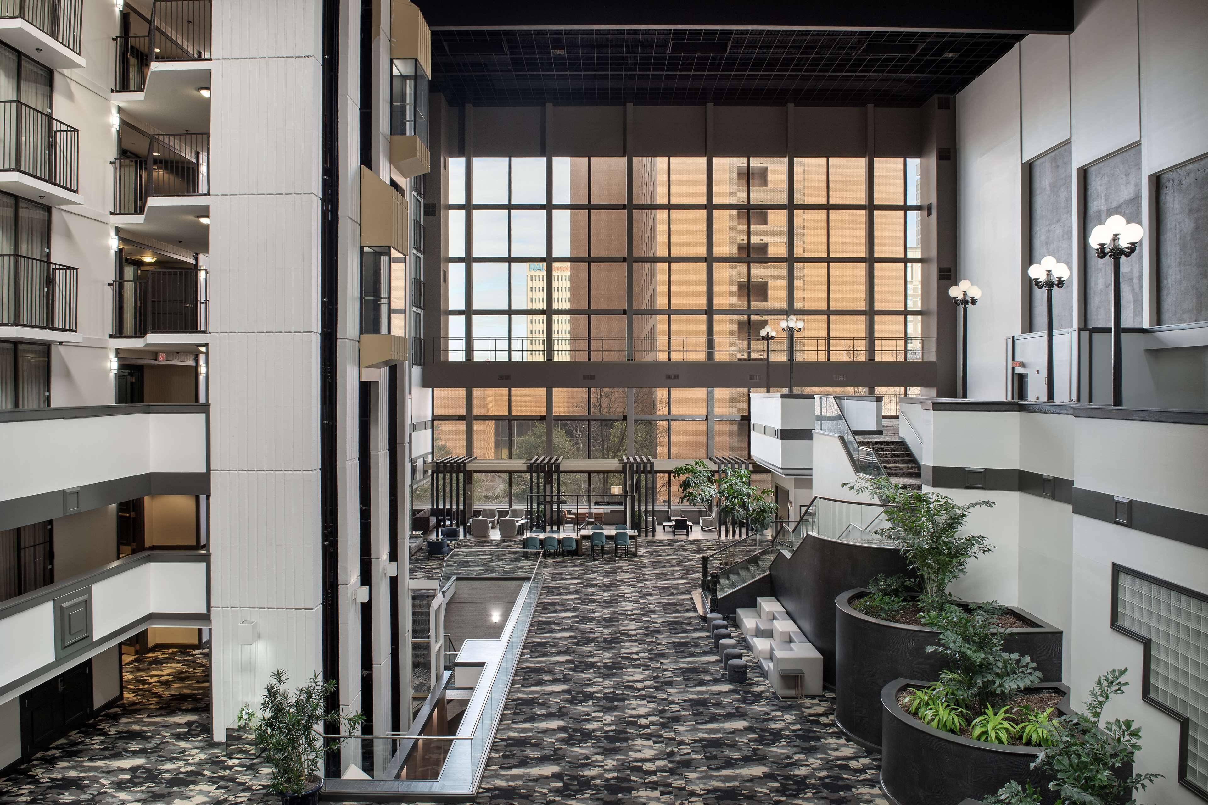 A spacious atrium with a high ceiling, large windows, and a central water feature.