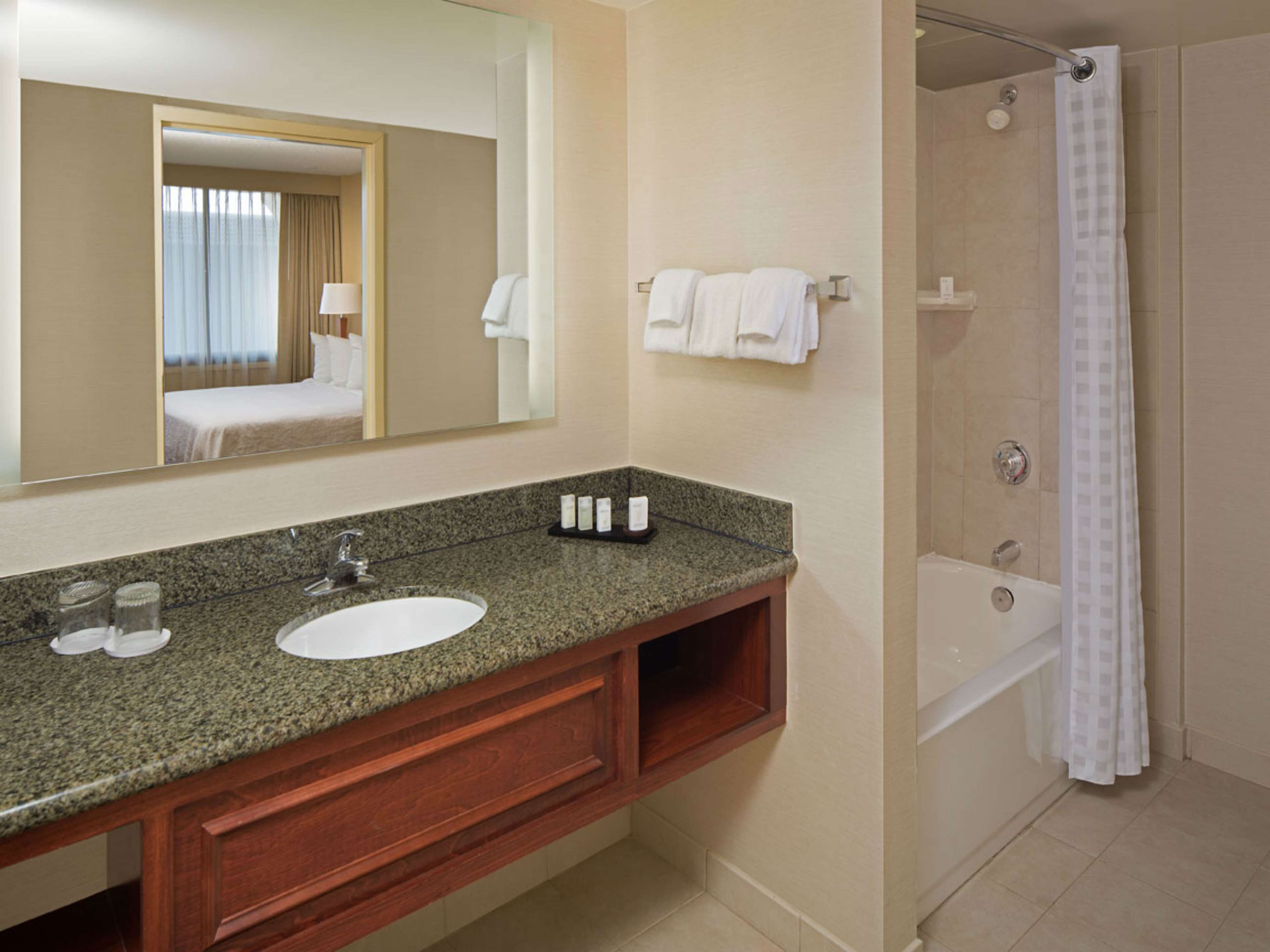 A bathroom with a granite countertop, a sink, a mirror, a shower, and a bathtub.
