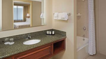 A bathroom with a granite countertop, a sink, a mirror, a shower, and a bathtub.