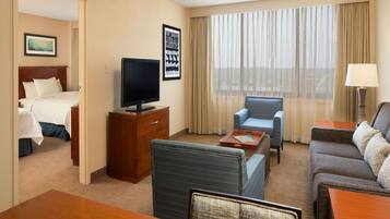 A hotel room with a bed, a TV, a desk, a sofa, and a chair.