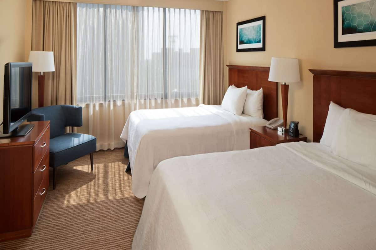 A hotel room with two beds, a TV, a desk, and a chair.