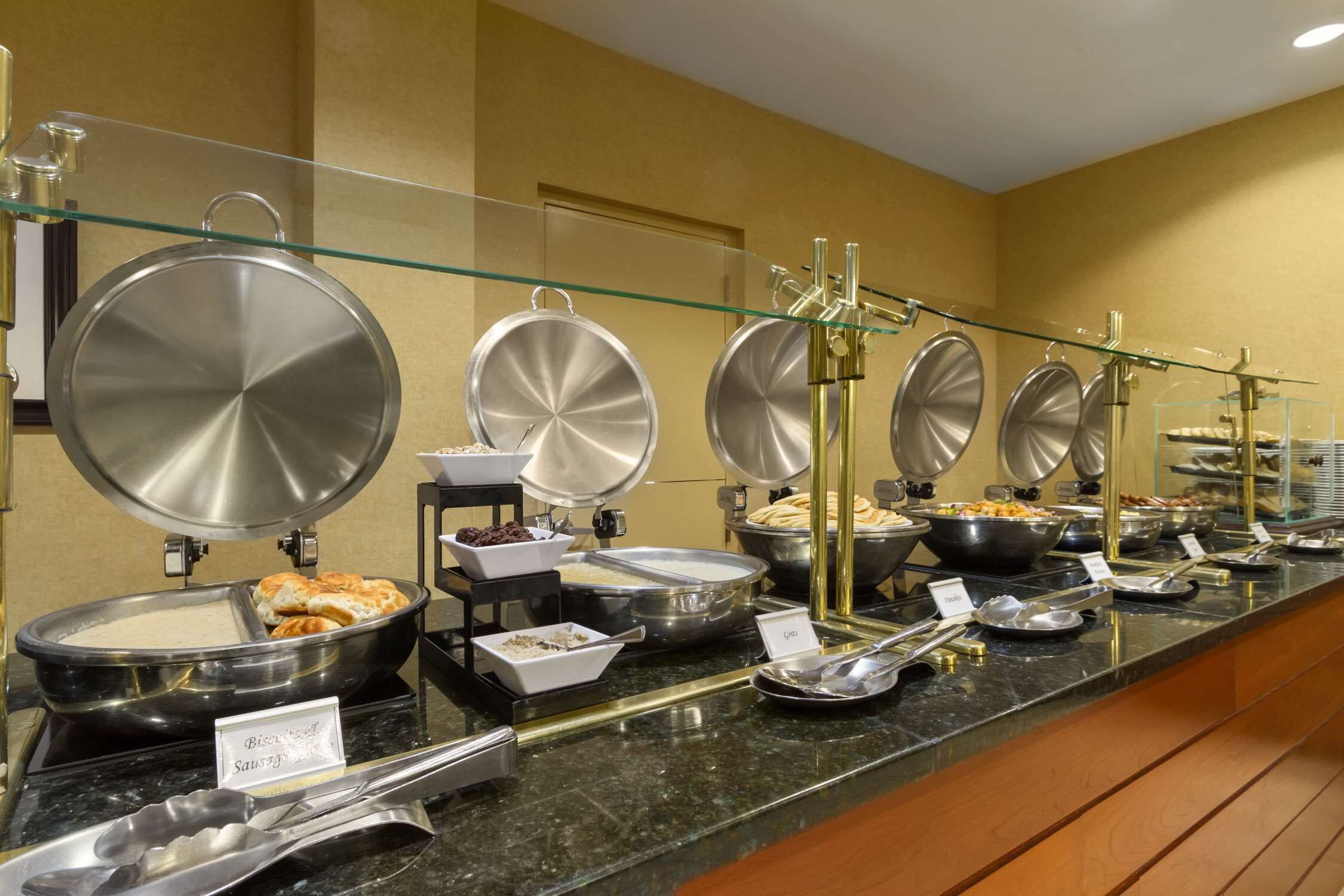 A buffet setup with various food items and serving utensils.