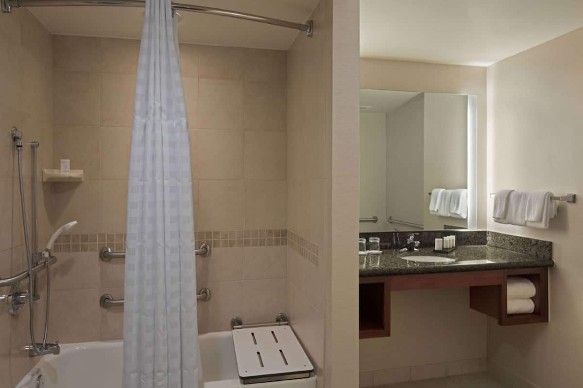A bathroom with a bathtub, shower, and a vanity with a mirror.