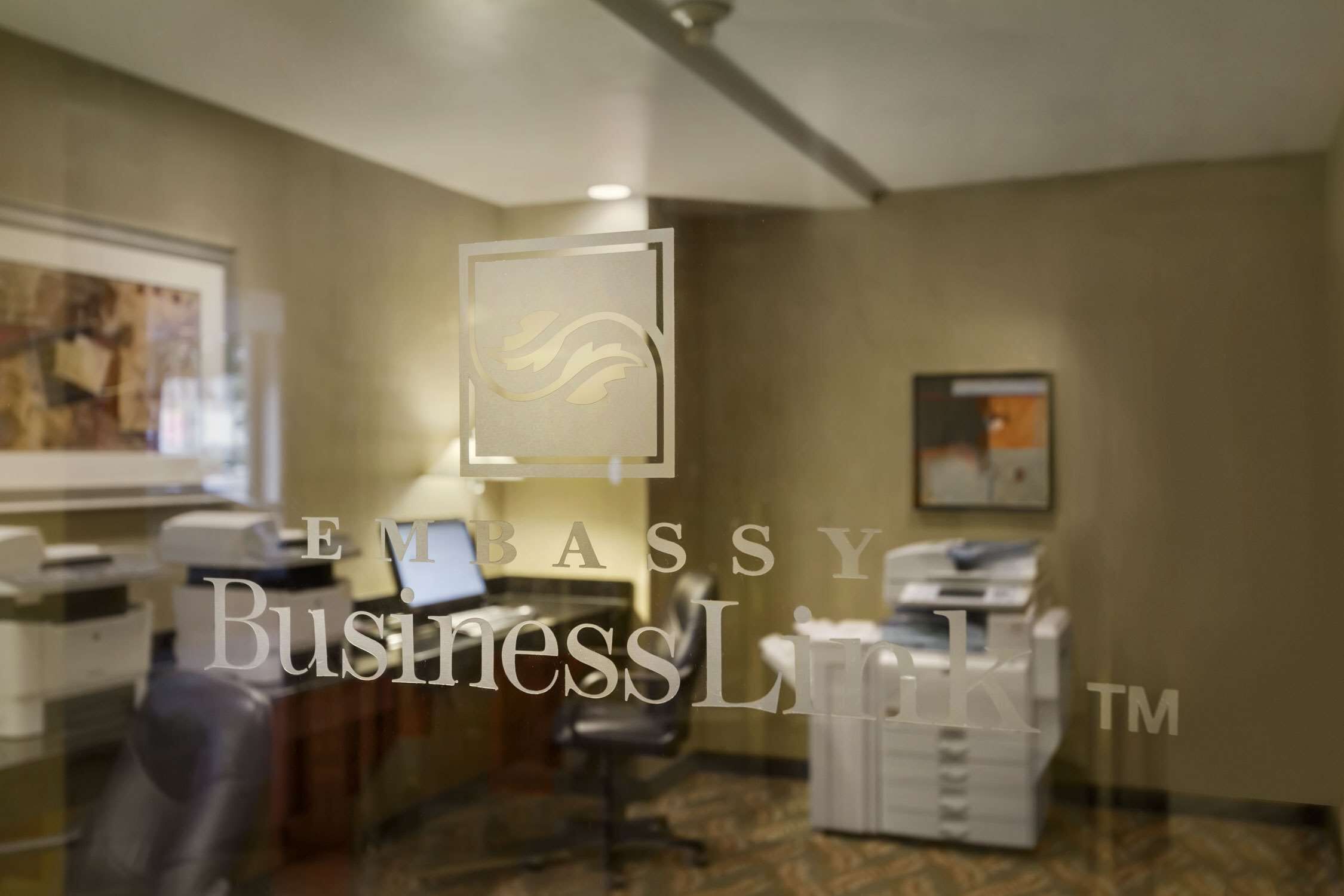 A business lounge with a desk, chairs, and a printer.