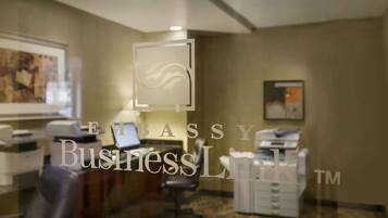 A business lounge with a desk, chairs, and a printer.