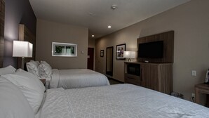 A hotel room with two beds, a TV, and a framed picture on the wall.