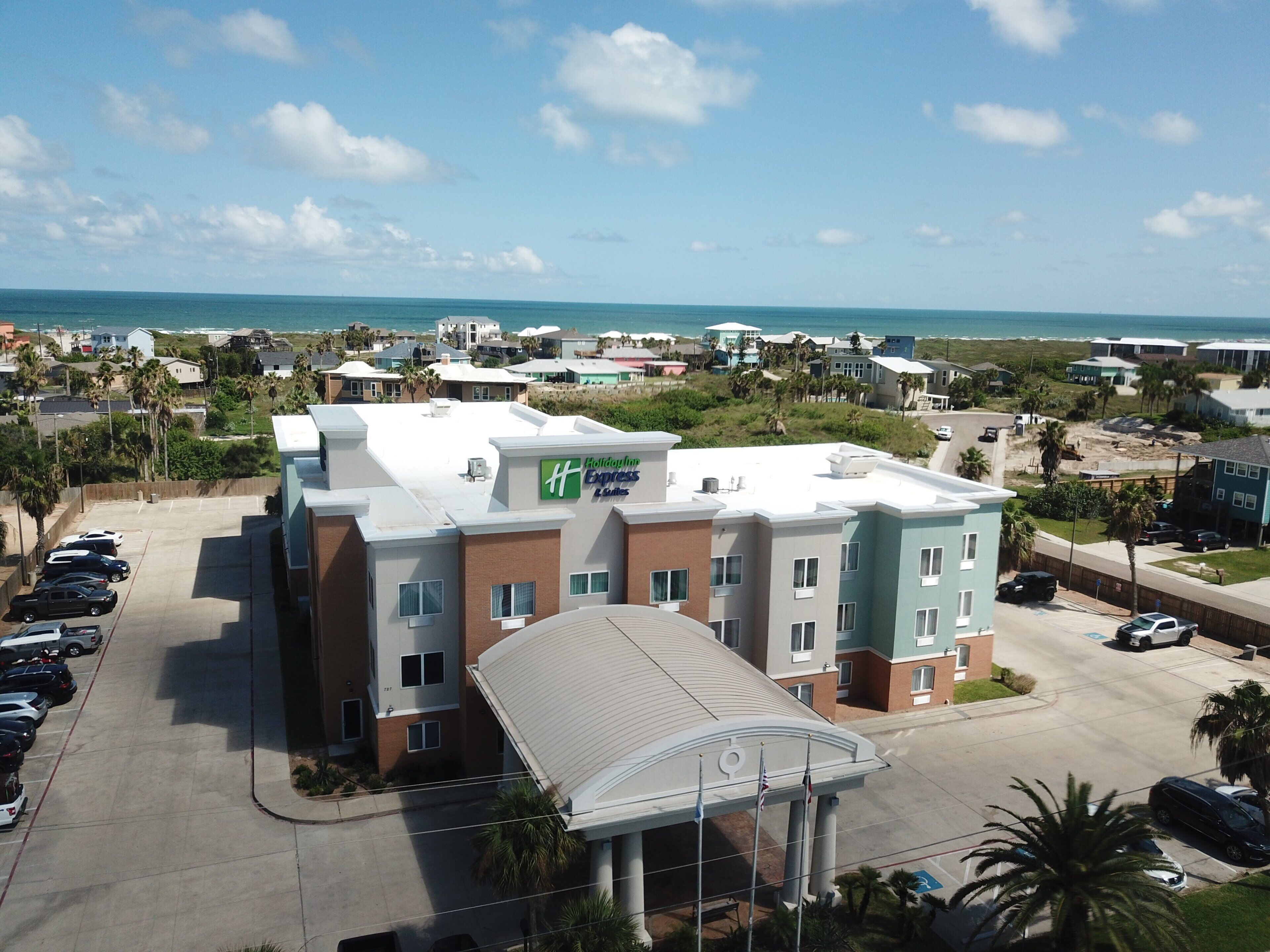 A multi-story hotel with a parking lot, a beach view, and a sign for Holiday Inn Express.