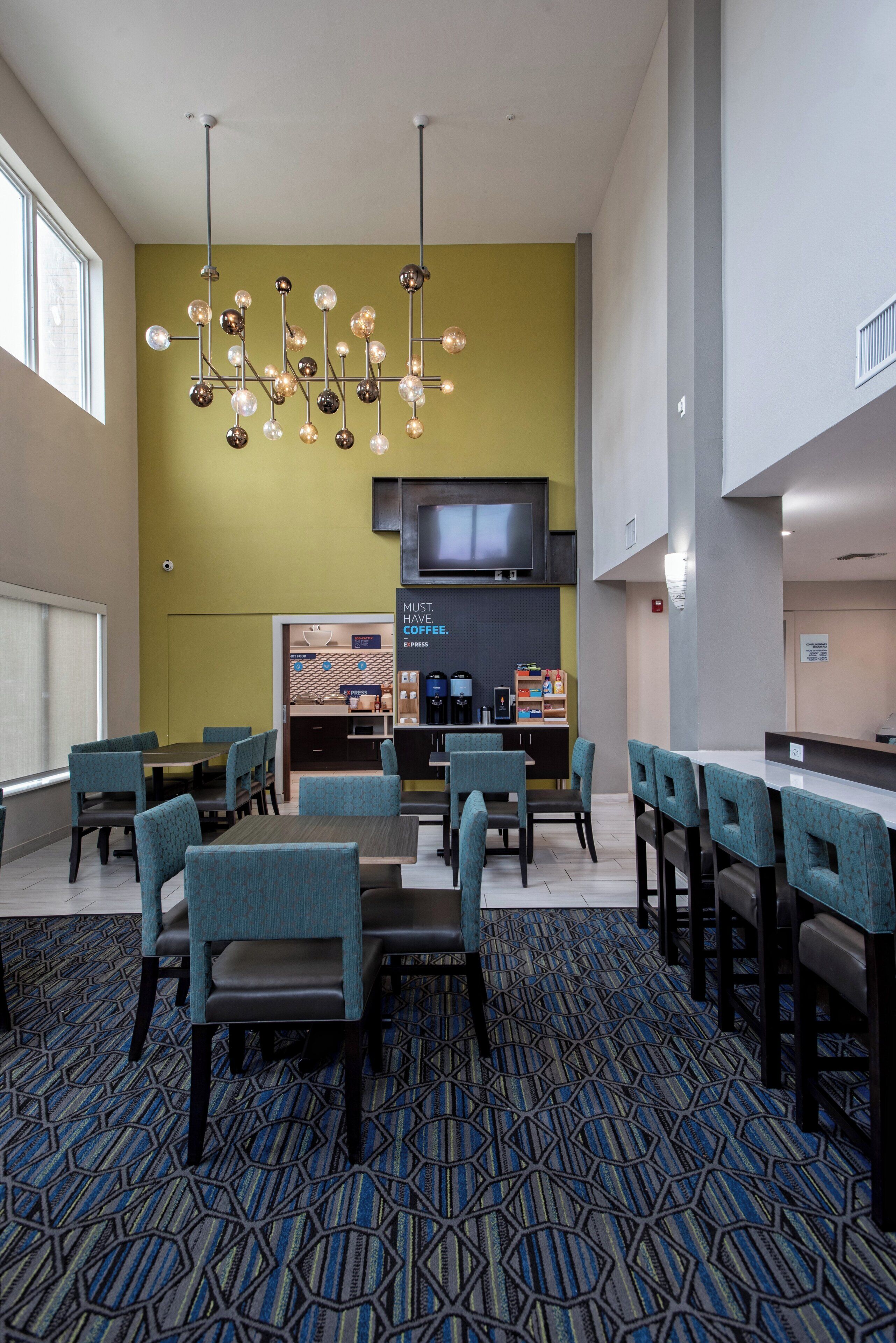 A hotel lobby with a coffee bar, seating area, and a television screen.