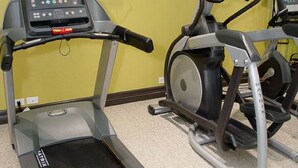 A gym with treadmills, stationary bikes, and a television mounted on the wall.
