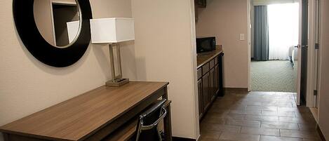 A hotel hallway with a wooden console table, a wall-mounted mirror, and a microwave.