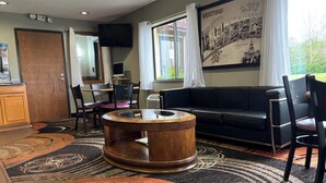 A cozy room with a wooden coffee table, a black sofa, and a dining area with chairs and a table.