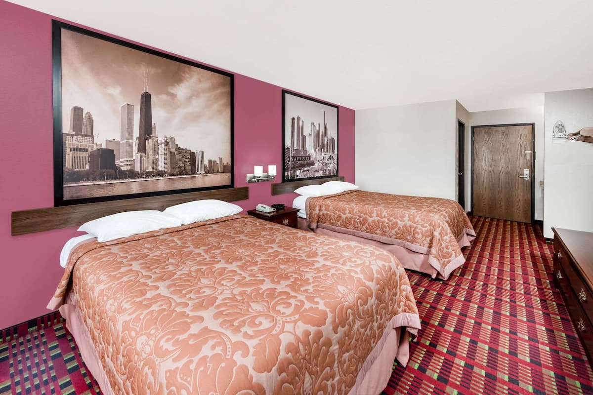 Quarto de hotel com duas camas, um quadro com vista para a cidade, tapete estampado e porta de madeira.
