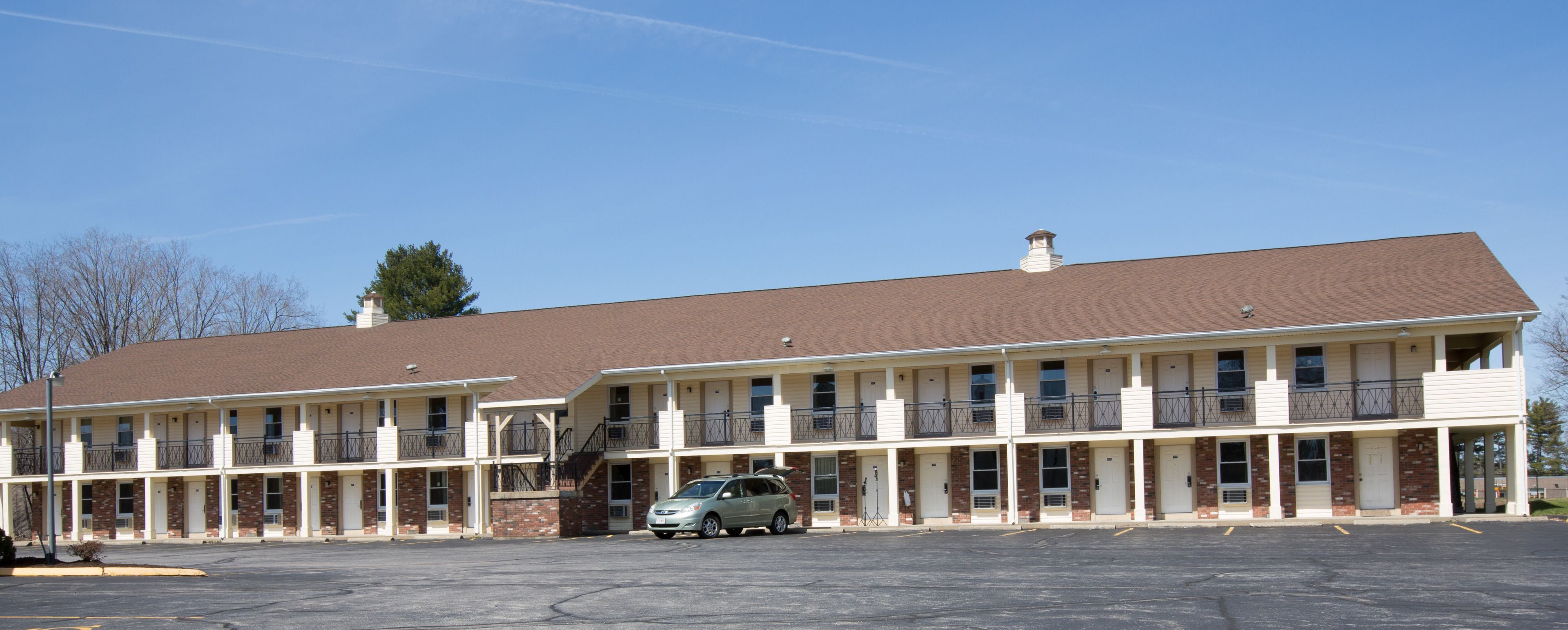 Ein mehrgeschossiges Motel mit Parkplatz und einem davor stehenden Auto.