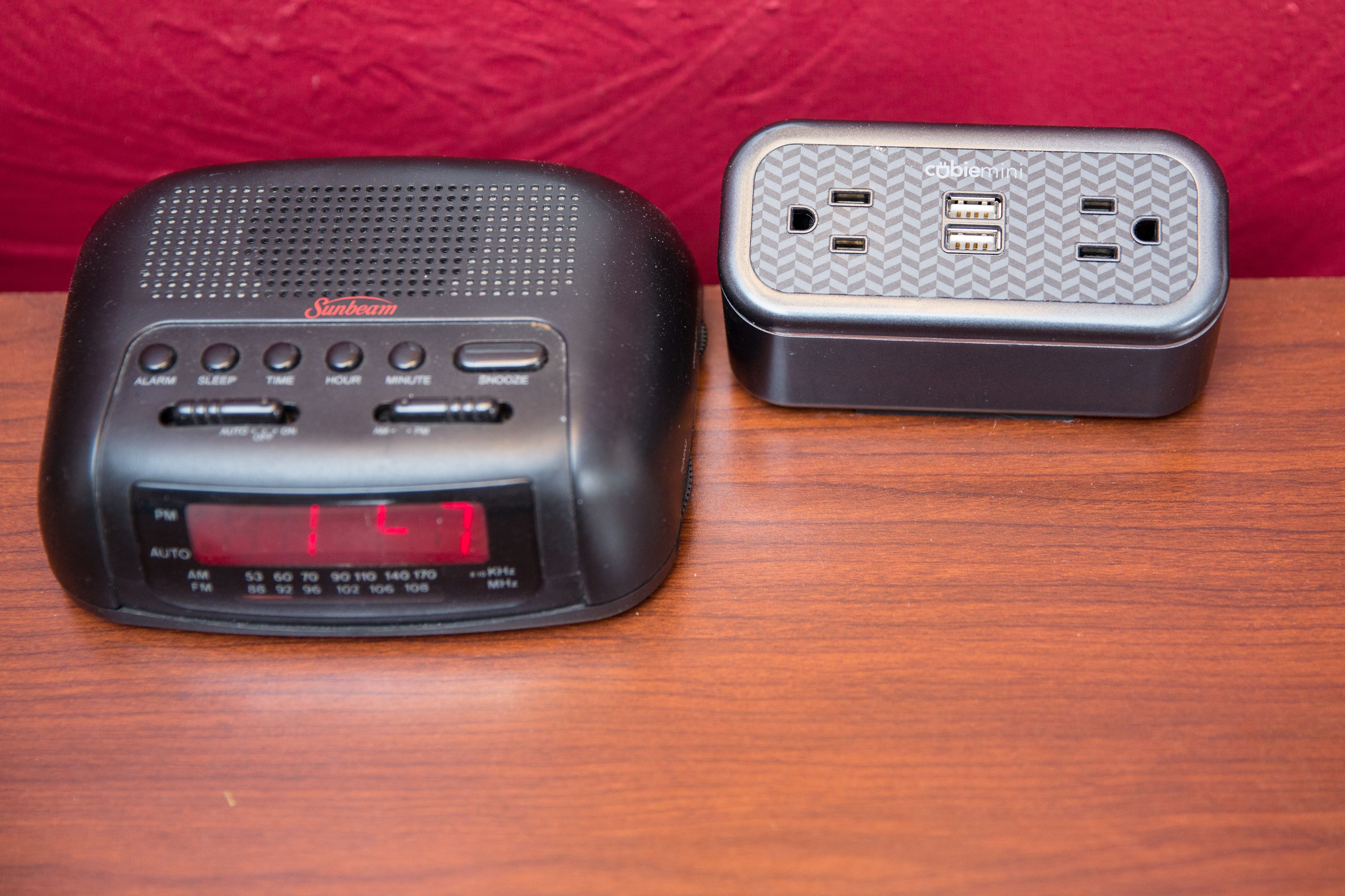 Un equipo de radio negro con pantalla digital y un adaptador de corriente gris con varios puertos.